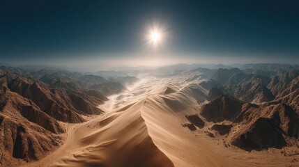 Naklejka premium Vast desert landscape with a bright sun shining over rugged mountains and sand dunes under a clear blue sky