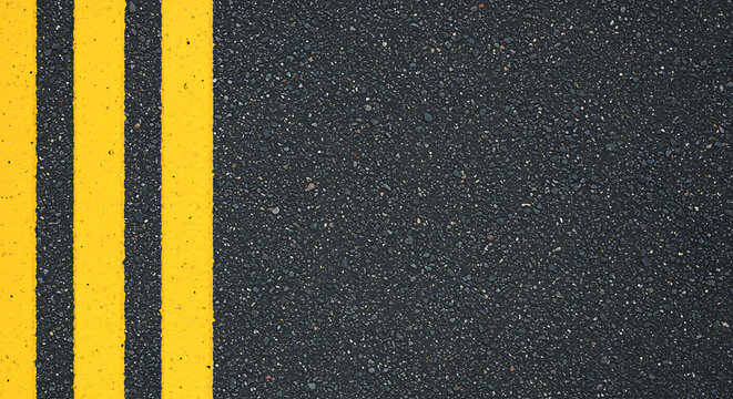 Close up overhead view of bright yellow double traffic lines painted on a textured dark asphalt road surface creating a bold graphic pattern