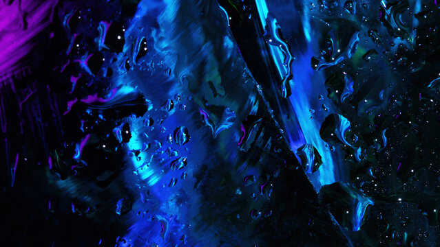 Abstract close-up of water droplets on a glass surface illuminated by vibrant blue and purple neon lights with smooth textures and reflections.