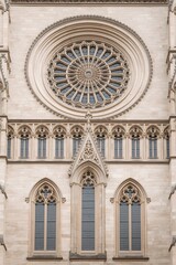 Obraz premium Gothic cathedral facade with ornate rose window and pointed arch stained glass windows, showcasing intricate medieval architecture, stone craftsmanship, and historic religious design elements.