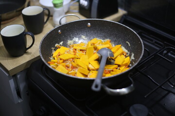 Vegetables frying in deep pan on gas stove