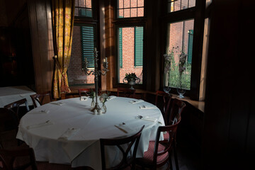 Traditional restaurant interior with round table set for dinner and candlelight ambiance