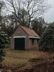 Brick utility building surrounded by bare trees in forest setting