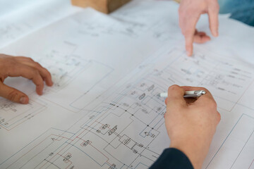 Hands working on detailed technical drawings and architectural blueprints