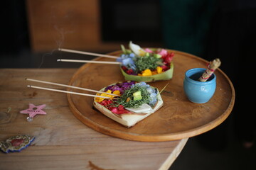 Traditional Balinese offering baskets (canang sari) arranged on a wooden tray, decorated with fresh flowers and aromatic incense sticks