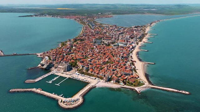 Drone capture Pomorie Bulgaria old town peninsula surrounded Black Sea clear turquoise waters marina boats sandy shores summer travel scene historic architecture vacation landmark popular destination