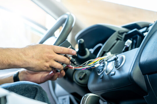 Service technician connecting wires during car dashboard repair, showing vehicle electronics installation, auto maintenance, modern multimedia upgrade, diagnostic process, professional car service.