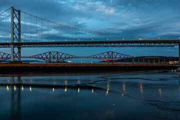 Taken at dusk, a view down the Firth of Forth from Queensferry, with dark blue sky and reflections in the water.