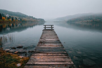 Serene autumnal lake scene, misty, calm water reflecting hills, wooden dock