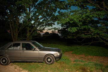 Classic sedan parked under trees during evening golden hour creating nostalgic atmosphere