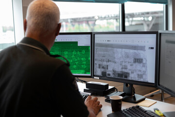 Customs officer operating dual monitor setup with green scanning display and X-ray imaging systems
