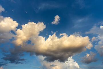 Fluffy white clouds drift across a bright blue sky on a beautiful summer day