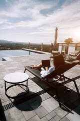 Relaxation by the pool with a laptop in the afternoon sun at a luxurious outdoor lounge