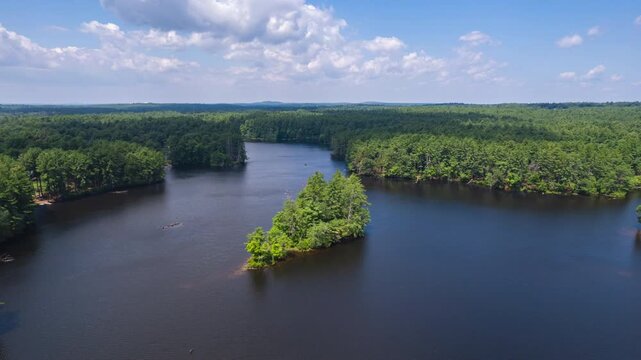 Aerial time lapse of American forest landscape with natural lake and cloud shadows on water surface. Hyperlapse shot. Harold Parker forest in MA, USA.