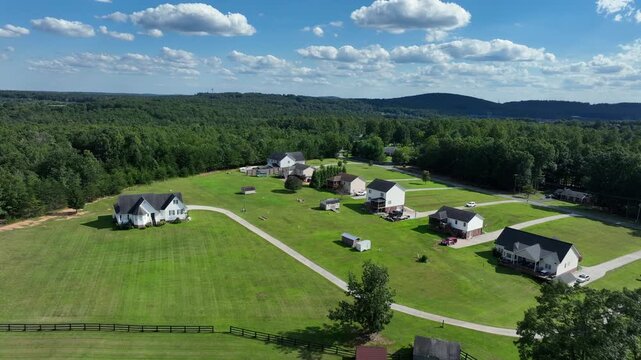 Aerial flyover charming American suburb with modern single-family homes and diverse architectural styles. Gabled roofs, porches and manicured lawns in new suburbia.Lush greenery in suburbia with pool.