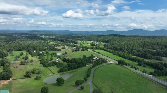Charming American farmstead with house, waving flag of USA and large property. Rising drone wide shot. Rural area of viginia with traffic on highway in distance. Summertime in suburbia.