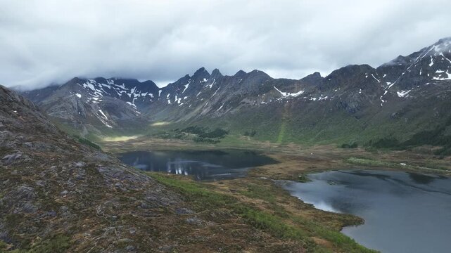 Drone reveals Hopsvatnet, Hopspollen and E10 road south of Svolvaer with rugged Lofoten peaks in spring
