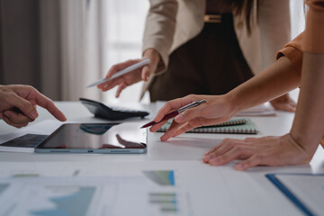 Business colleagues are collaborating and reviewing financial statistics displayed on a digital tablet, using a pen to point at specific data points and discuss growth opportunities