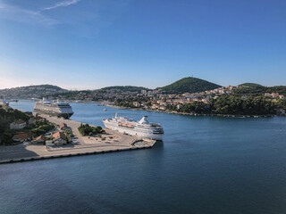Small classic cruiseship cruise ship liner in Dubrovnik port, Croatia during summer Adria Mediterranean cruising with scenic landscape and city skyline on sunny day