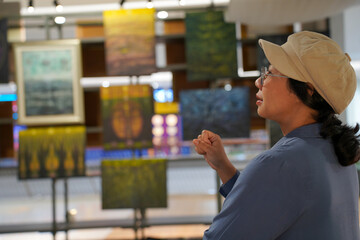 Woman observing artwork in modern art gallery. Captures moment of thoughtful appreciation, ideal for themes of creativity, inspiration, education, and cultural exploration.