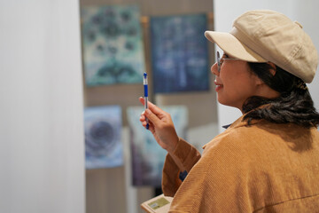 Woman observing artwork in modern art gallery. Captures moment of thoughtful appreciation, ideal for themes of creativity, inspiration, education, and cultural exploration.