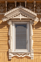 Picturesque window of an old wooden house with a carved frame