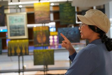 Woman observing artwork in modern art gallery. Captures moment of thoughtful appreciation, ideal for themes of creativity, inspiration, education, and cultural exploration.