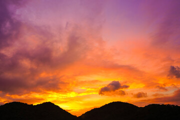 sunset sky with dramatic purple, pink, and orange clouds over silhouette mountains. Captures peaceful nature and magical twilight moment for background, travel, and nature concepts.
