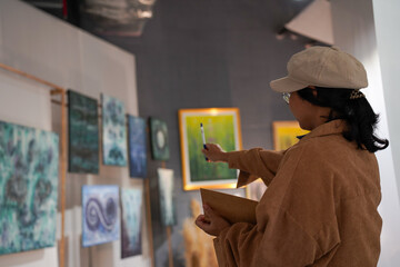 Woman observing artwork in modern art gallery. Captures moment of thoughtful appreciation, ideal for themes of creativity, inspiration, education, and cultural exploration.