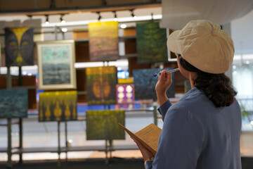 Woman observing artwork in modern art gallery. Captures moment of thoughtful appreciation, ideal for themes of creativity, inspiration, education, and cultural exploration.
