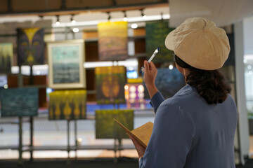 Woman observing artwork in modern art gallery. Captures moment of thoughtful appreciation, ideal for themes of creativity, inspiration, education, and cultural exploration.