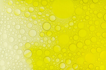 Macro abstract image of golden oil bubbles suspended in liquid, forming overlapping circular...