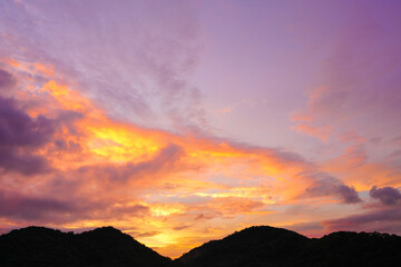 sunset sky with dramatic purple, pink, and orange clouds over silhouette mountains. Captures peaceful nature and magical twilight moment for background, travel, and nature concepts.