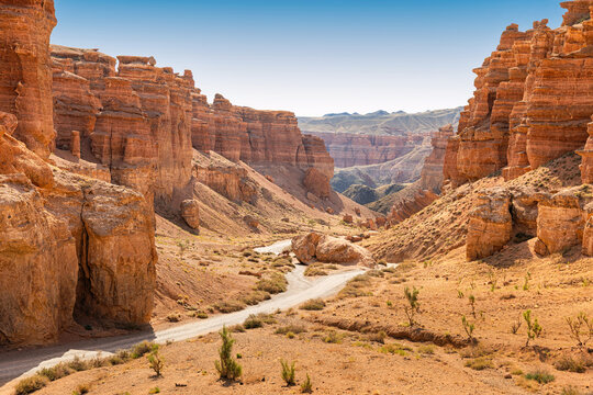 Majestic landscape of Charyn Canyon in Kazakhstan featuring unique rock formations, arid terrain, and a winding road under a clear blue sky