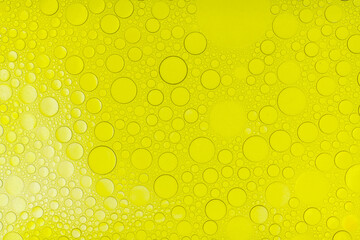 Macro abstract image of golden oil bubbles suspended in liquid, forming overlapping circular...