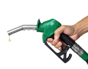 A green fuel pump nozzle held in a hand with a droplet of fuel forming at the spout.