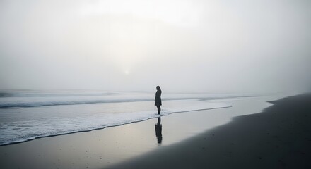 A lone woman's silhouette stands on a deserted, foggy beach at sunrise, with her reflection on the wet sand, looking out at the calm ocean waves