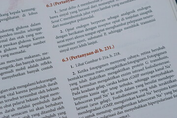 A close-up of an open medical textbook, showing detailed text and diagrams about human physiology and biology. This image represents study, education, research, and the journey of a medical student.