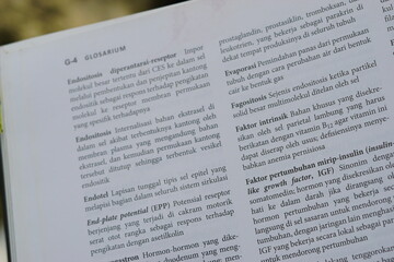 Obraz premium A close-up of an open medical textbook, showing detailed text and diagrams about human physiology and biology. This image represents study, education, research, and the journey of a medical student.