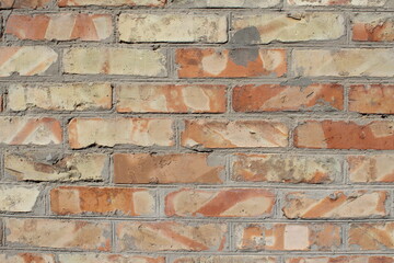 Laid out masonry of a wall made of red, uneven bricks with spots and streaks, fragment.