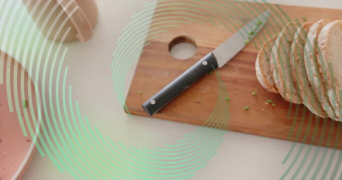 Knife starting slicing bread on board, crumbs scattering, making avocado egg toast and mug on plate