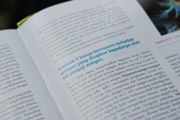 Obraz premium A close-up of an open medical textbook, showing detailed text and diagrams about human physiology and biology. This image represents study, education, research, and the journey of a medical student.