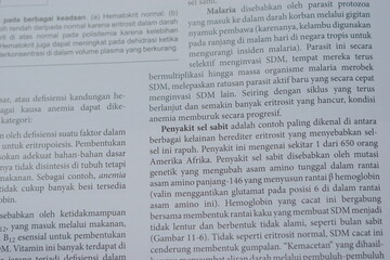 Obraz premium A close-up of an open medical textbook, showing detailed text and diagrams about human physiology and biology. This image represents study, education, research, and the journey of a medical student.