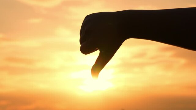 With a thumbs-down sign against the sunset, this image conveys rejection and disagreement. It further represents warning, disappointment, reflection, and the importance of honest expression in life.
