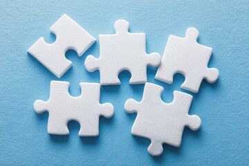 Obraz premium White puzzle pieces scattered on light blue surface