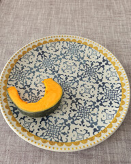 Pieces, slices of pumpkin on porcelain plate with blue pattern. Farm products and healthy eating. Kitchen and home cooking.