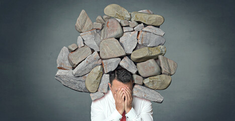 Businessman with head in hands under heavy burden symbolizing crisis and stress