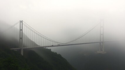 Suspension bridge shrouded in thick fog, disappearing into the mist