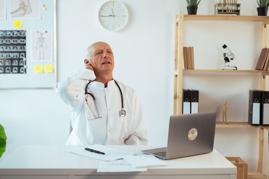 Healthcare worker tired. senior elderly male doctor suffering neck and backache problem caused hardworking.