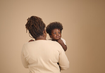 Mother embraces her toddler over her shoulder, capturing themes of comfort, security, and family...